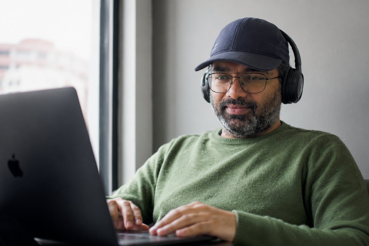 Ramesh wearing headphones and a cap, sitting in front of a laptop at Codified Commerce.