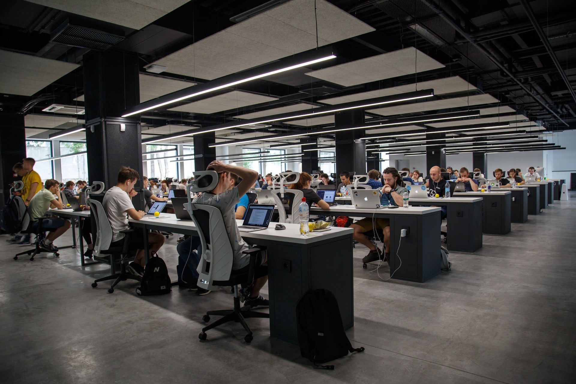 Modern office space with rows of desks and people working.