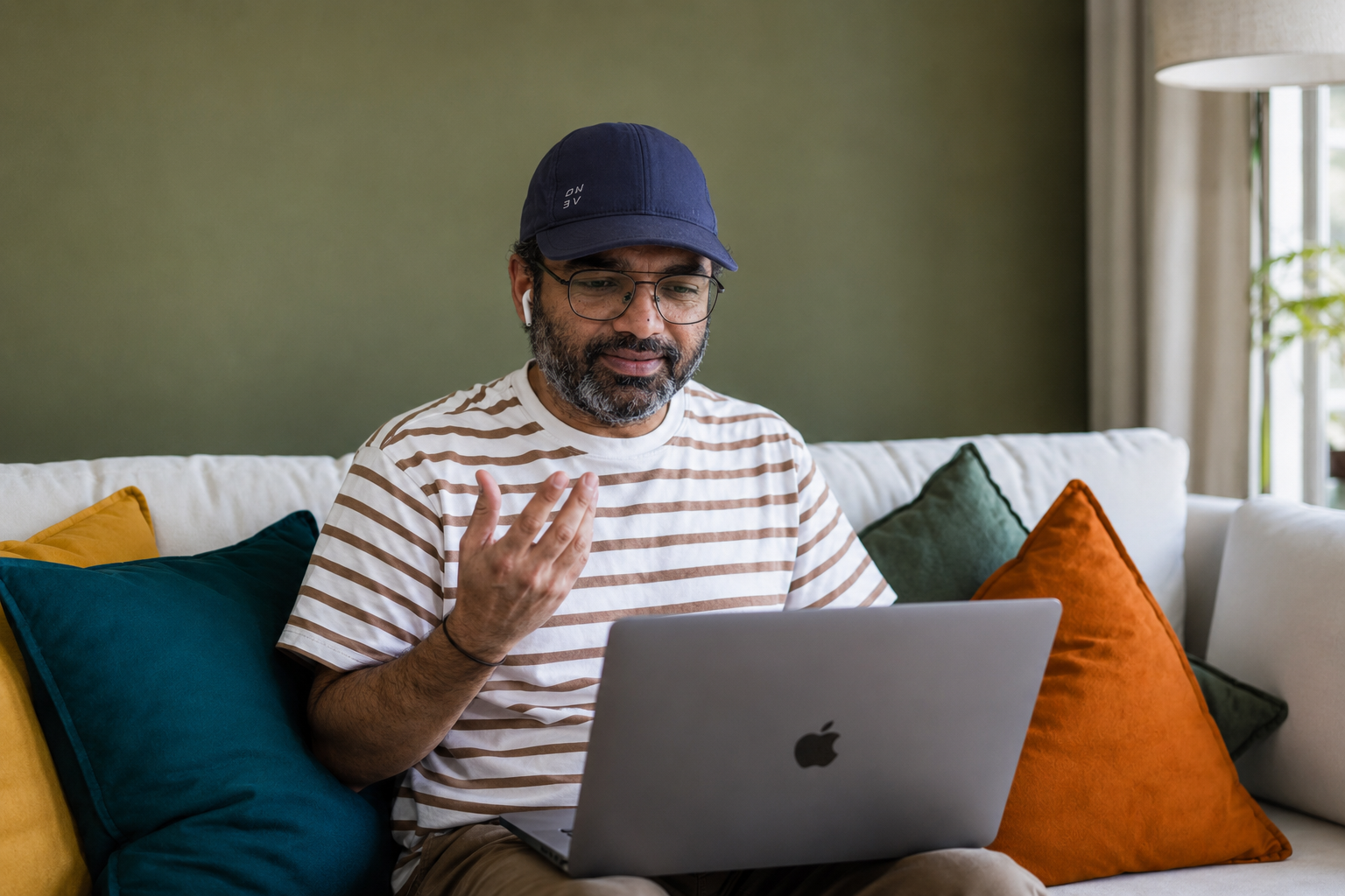Ramesh using a laptop on a couch with colorful pillows at Codified Commerce.